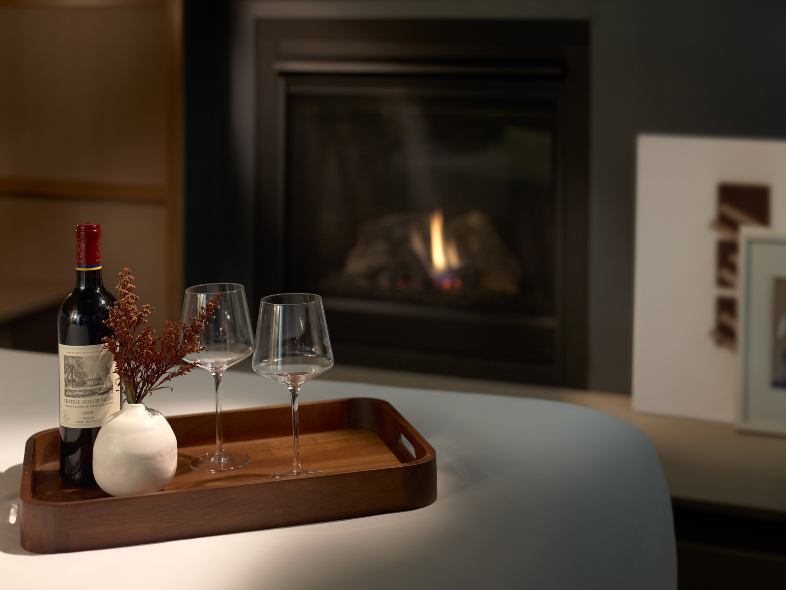 Tray with wine and wineglasses on the bed with a fireplace in the background