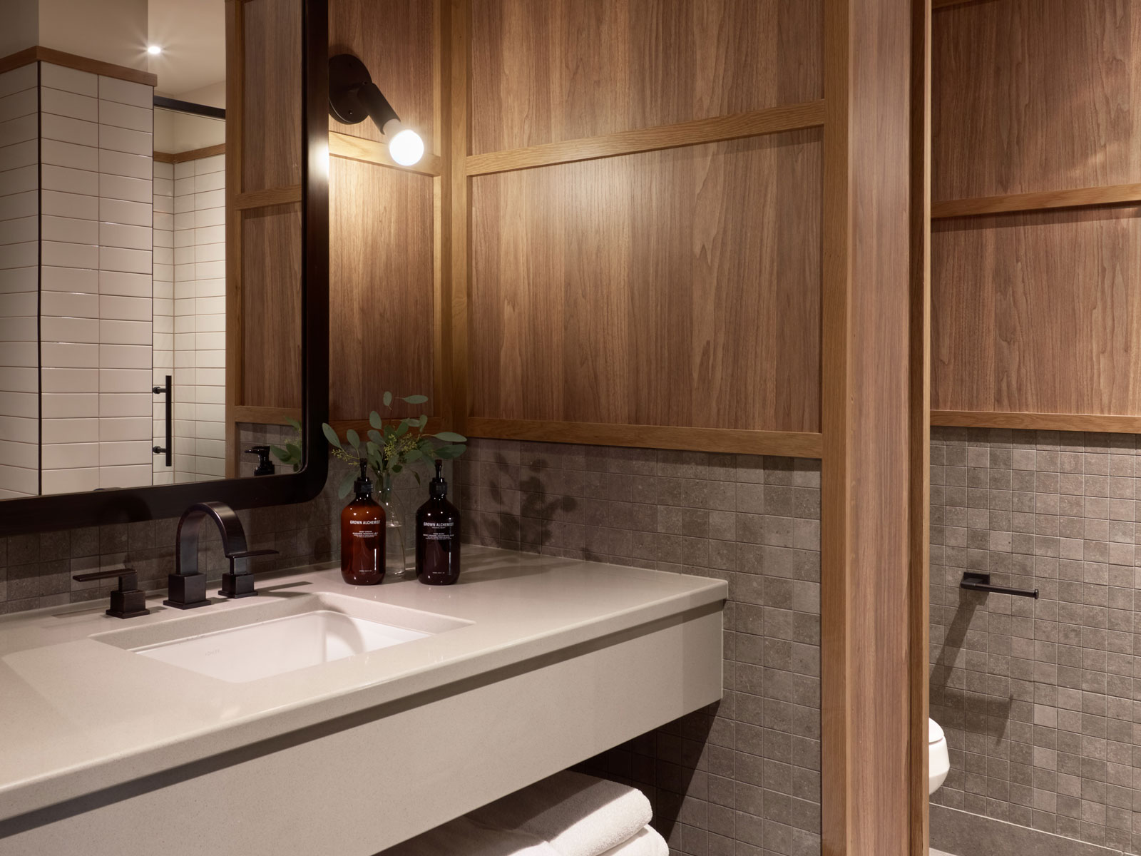 Guestroom Vanity Bathroom vanity with square gray tile and wood paneling