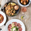 Top-down view of a marble table with shrimp scampi al forno, beef carpaccio, arancini, and fritto misto