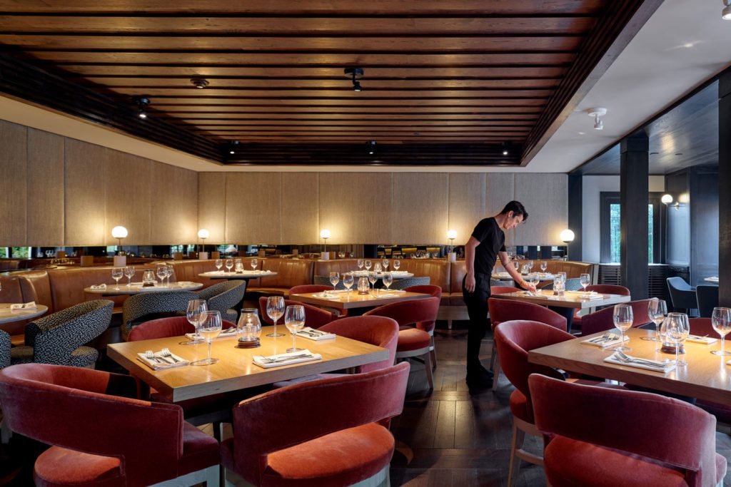 View of the Terrace Room dining room with romantic lighting and server arranging tableware