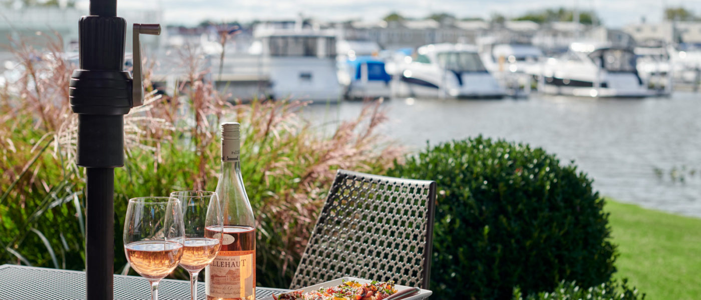Outdoor dining with a bottle of rosé wine and bruschetta, with a view of the New Buffalo harbor in the background