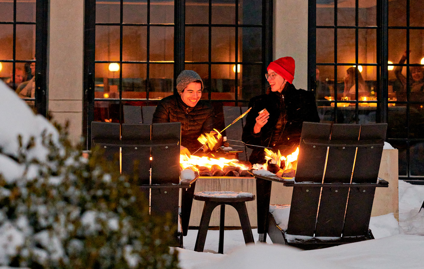 A couple roasting marshmallows for evening s'mores at the outdoor firepit at The Harbor Grand Hotel in New Buffalo, Michigan.