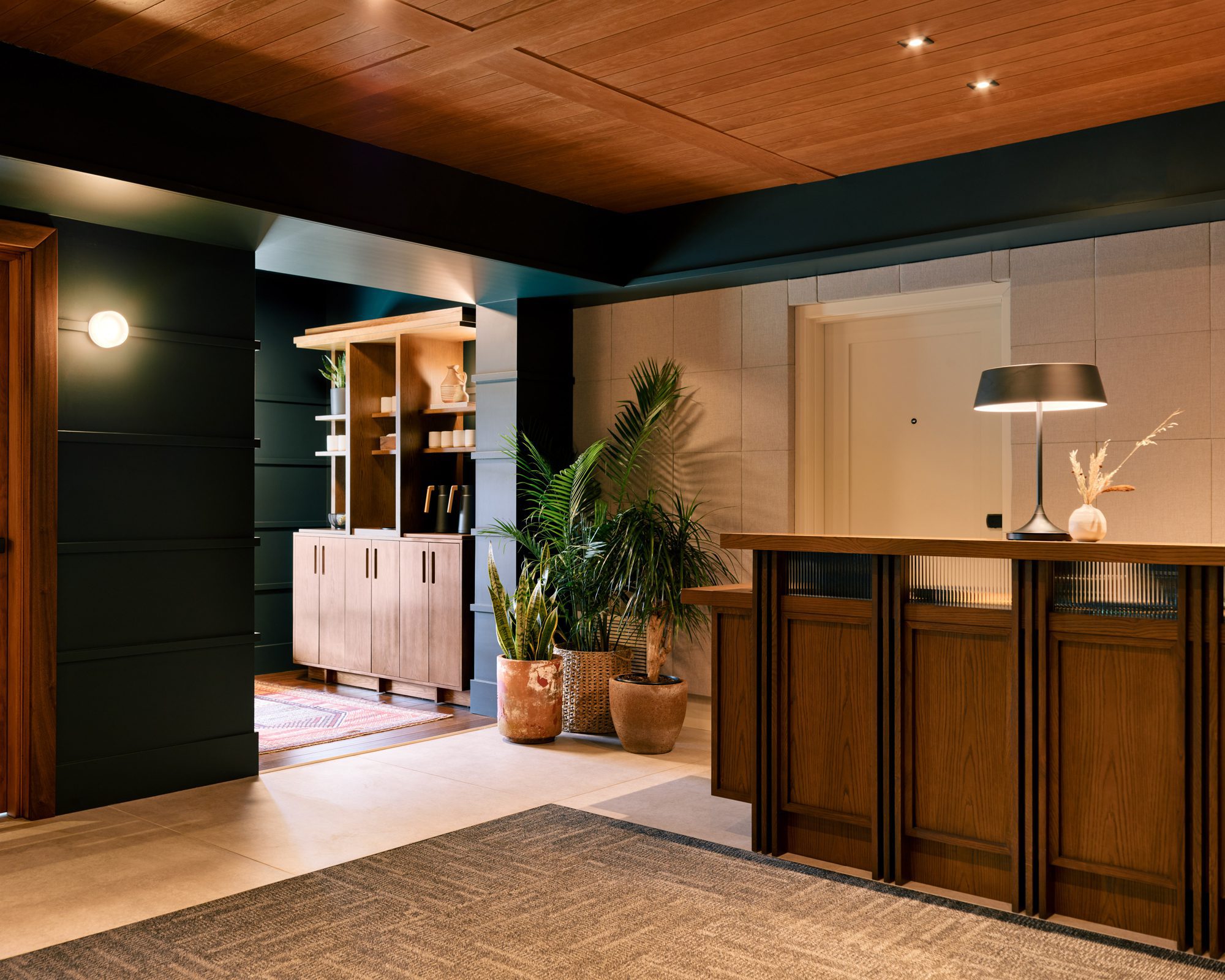 Harbor-Grand-Lobby-1000 reception of Harbor Grand with a wooden desk, potted flowers on the floor, wooden ceiling